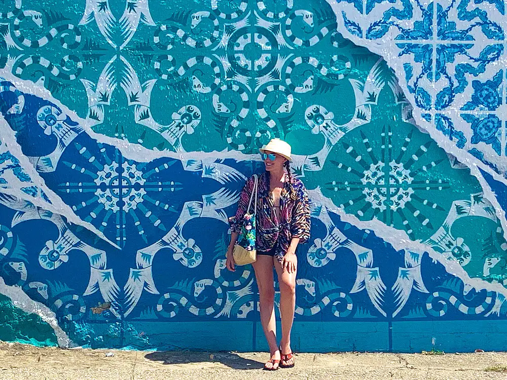 woman standing in front of blue and white street mural in San Nicolas Aruba