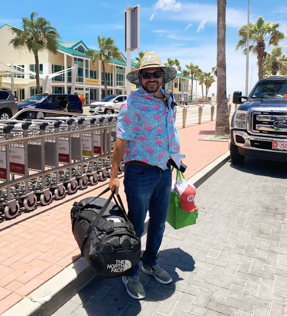 man holding luggage and standing outside the Aruba airport