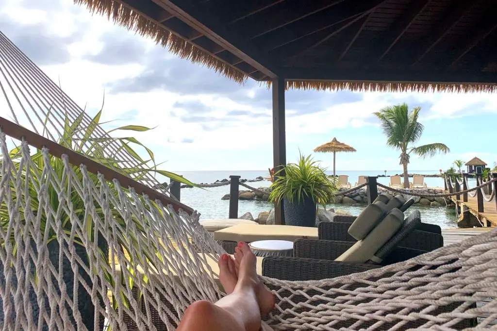 woman lying in hammock inside oceanfront cabana at Flamingo Beach on Renaissance Island in Aruba