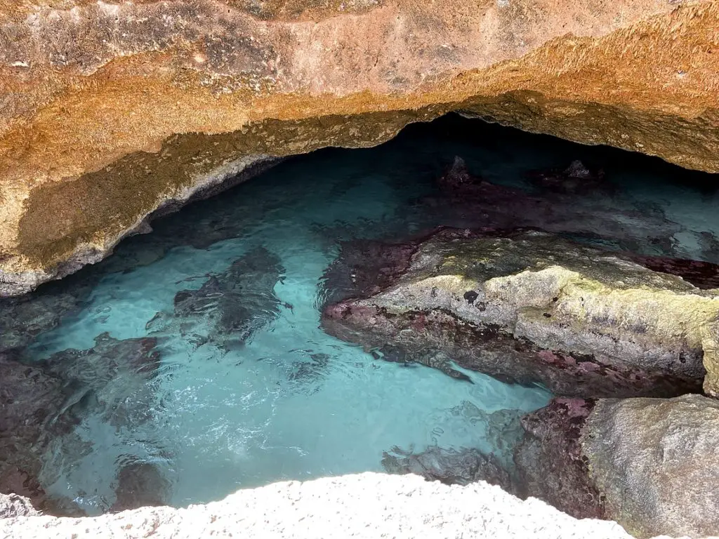 a hidden natural pool with clear blue water surrounded by tall rocks
