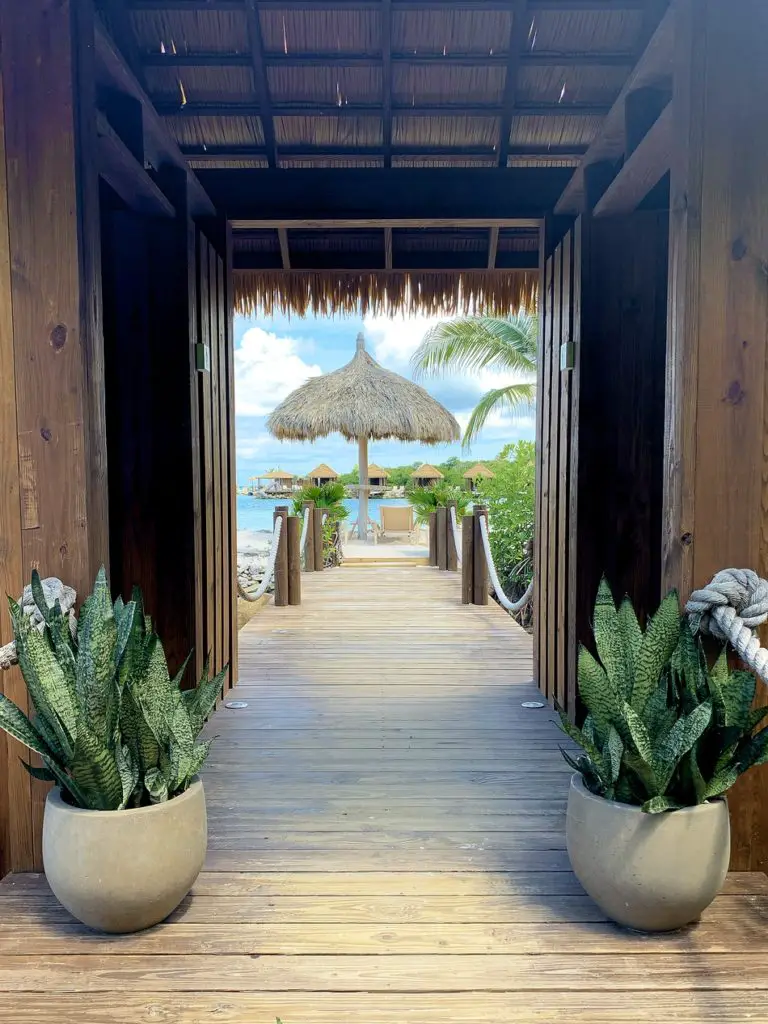 an open doorway overlooking a palapa and cabanas at Flamingo Beach on Renaissance Island