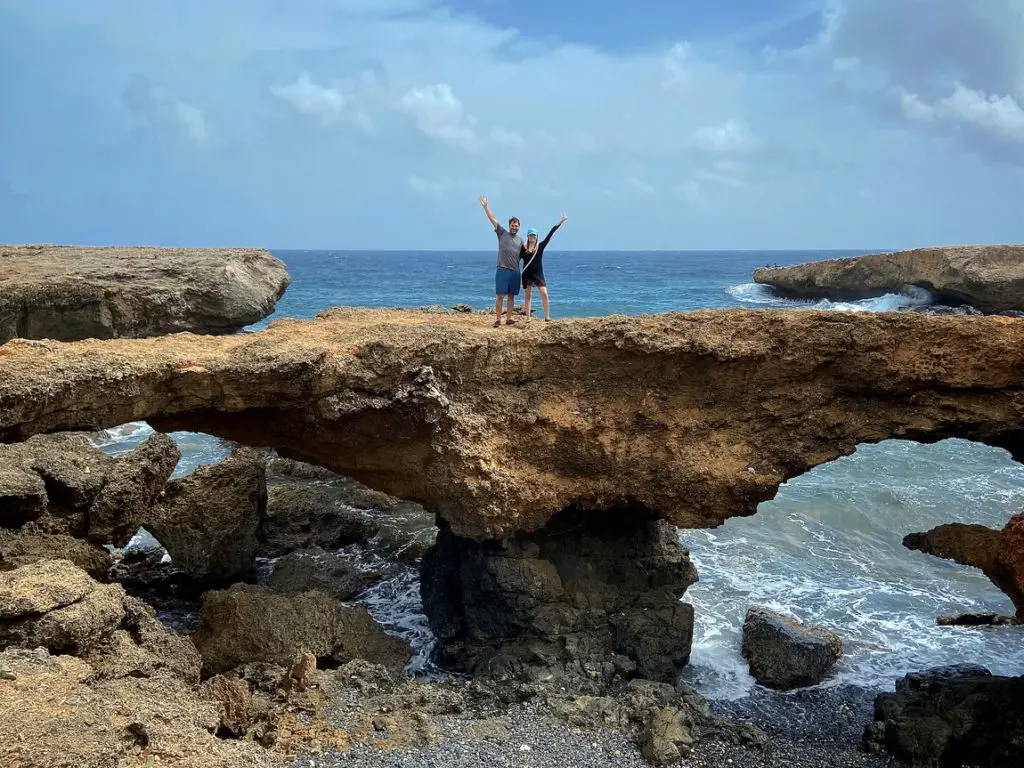 man and woman standing on the natural Tripod Bridge in Aruba