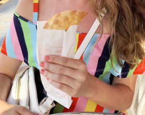 woman in a colorful striped dress holding a pastechi from The Pastechi House in Aruba