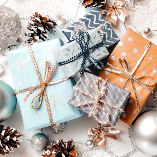 Wrapped gift boxes surrounded by silver ornaments and pine cones